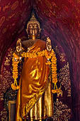 Wat Xieng Thong temple in Luang Prabang, Laos. The standing Buddha statue inside the pointed arch shrine. 